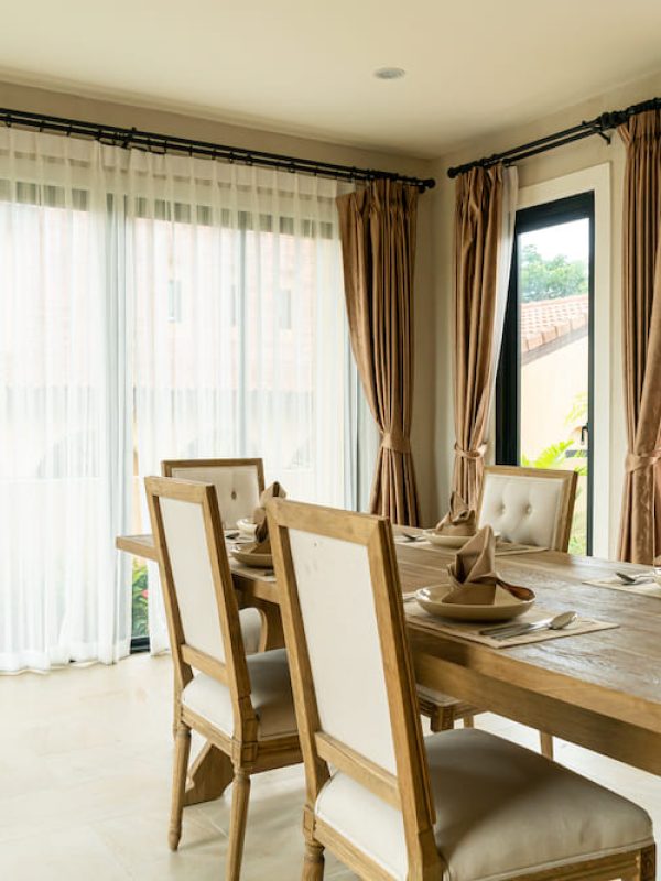 wood-dinning-table-in-a-room-with-curtain-and-window